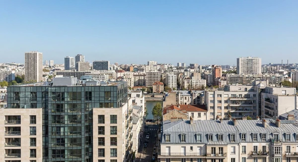 Vue de la skyline de Boulogne-Billancourt avec ses immeubles de façades variées et architectures urbaines modernes, sous un ciel dégagé. Au premier plan, un immeuble résidentiel ou tertiaire dont la façade montre clairement l'environnement urbain dense caractéristique de cette commune de l'Île-de-France. La photo doit montrer l'environnement urbain typique où intervient une entreprise de travaux en hauteur spécialisée en accès sur cordes.